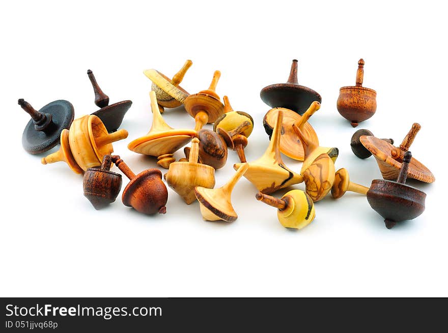 Spinning tops of different shapes, carved from wood, photographed against a white background