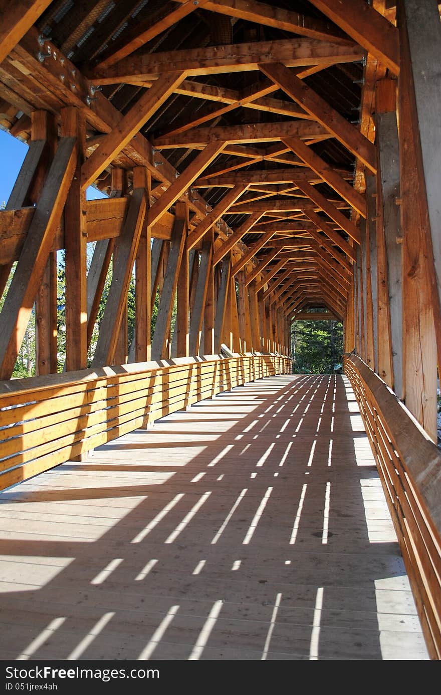 An inside view of the beams and angles of a wooden pedestrian bridge.