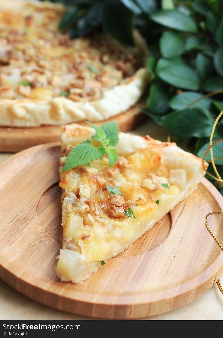 Puff pastry pie with pears and camembert cheese with walnuts and mint on a wooden plate