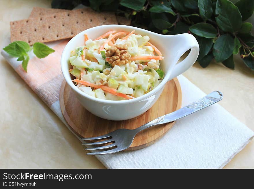 Salad with cabbage, carrot, apples and pears with walnuts in a bowl