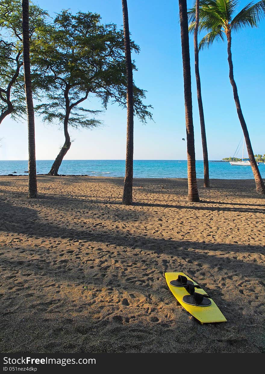 Yellow wakeboard on the sandy beach, in preparation for water activities. Yellow wakeboard on the sandy beach, in preparation for water activities