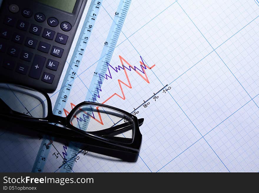 Calculator near ruler and spectacles on graph paper with diagram. Calculator near ruler and spectacles on graph paper with diagram