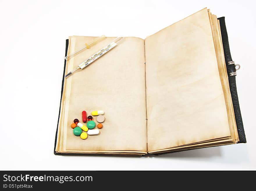 Tablets and thermometer on the old book. Tablets and thermometer on the old book