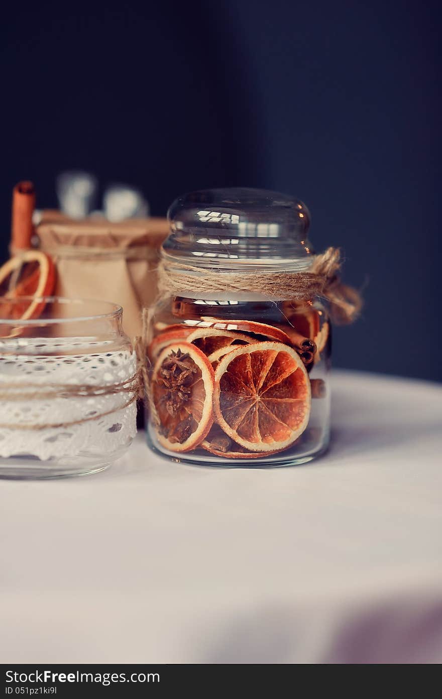 On a white table there are beautiful banks with dried segments of an orange. On a white table there are beautiful banks with dried segments of an orange