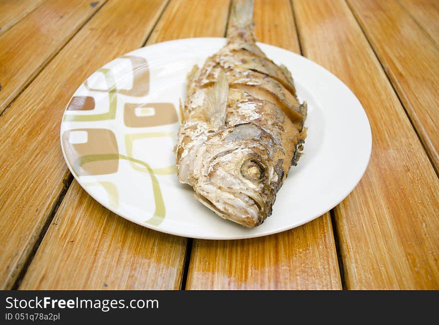 Fried fish on white dish and wood background, delicious thai food