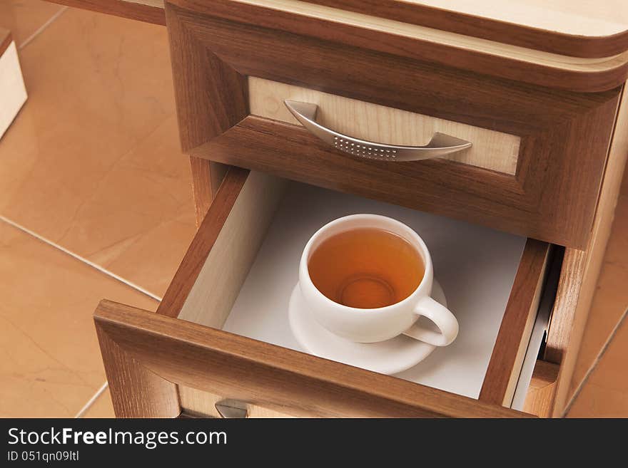 Cup of tea in open desk drawer. Cup of tea in open desk drawer