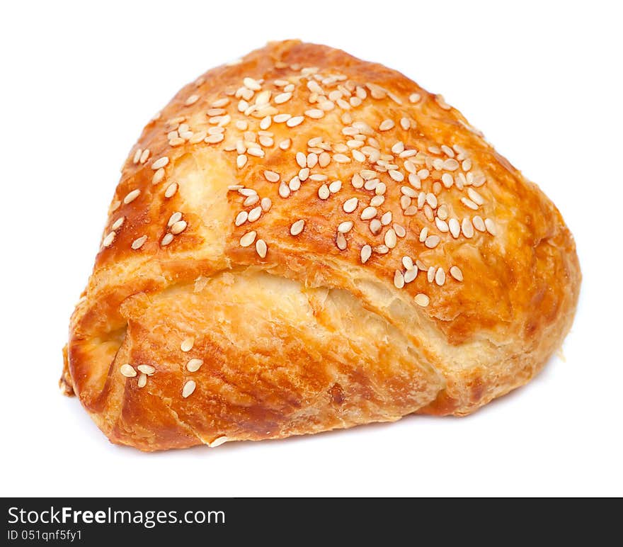 Pie from flaky pastry strewed with sesame seeds on a white background