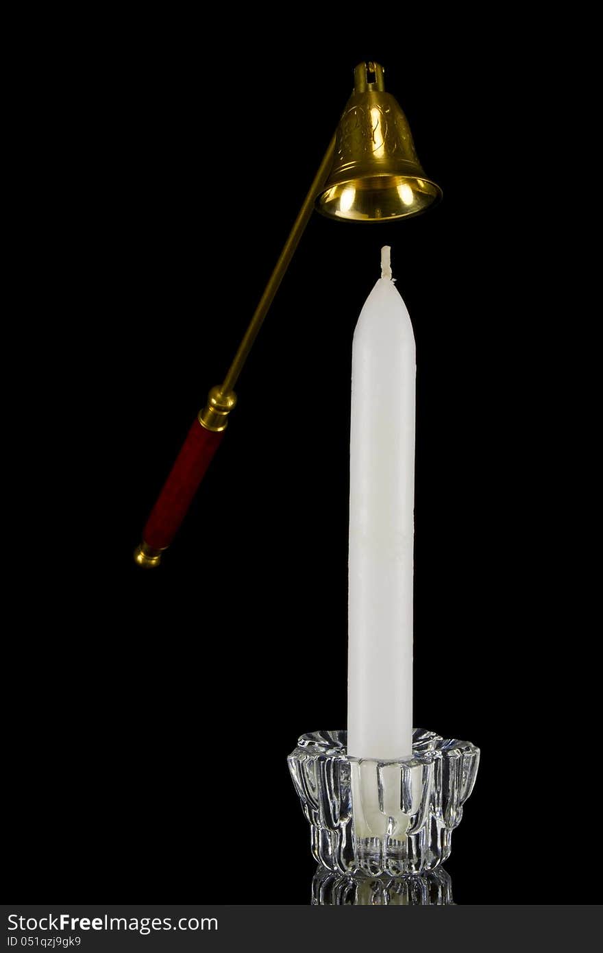 Candle in glass candlestick and candle snuffer on black background