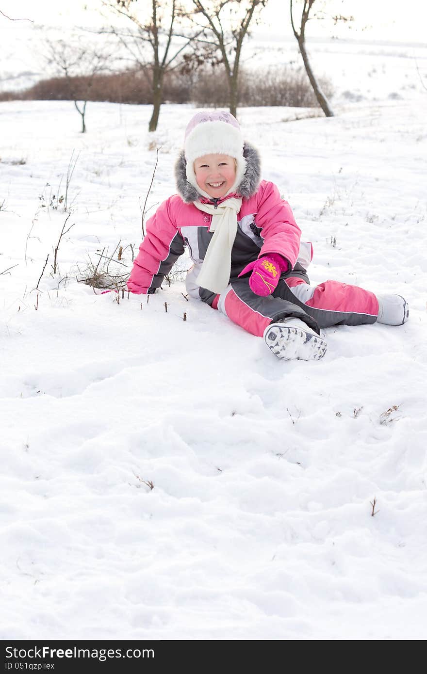 Cute little girl with a beautiful smile wearing a cuddly punk outfit and cap frolicking in winter snow with copyspace. Cute little girl with a beautiful smile wearing a cuddly punk outfit and cap frolicking in winter snow with copyspace