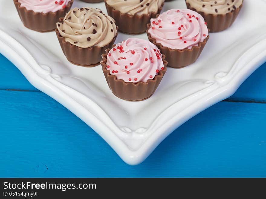 Elegant truffle filled, cupcake shaped chocolates on a white serving platter. Elegant truffle filled, cupcake shaped chocolates on a white serving platter.