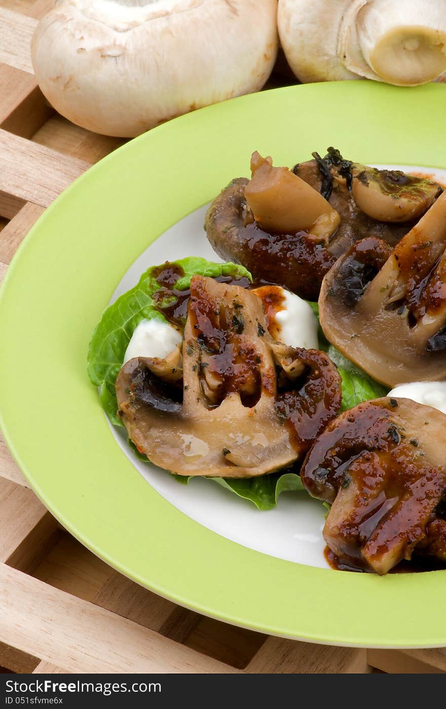 Cooked Mushrooms with Grill Sauce, Sour Cream and Greens on Plate closeup on Wood background and Raw Mushrooms