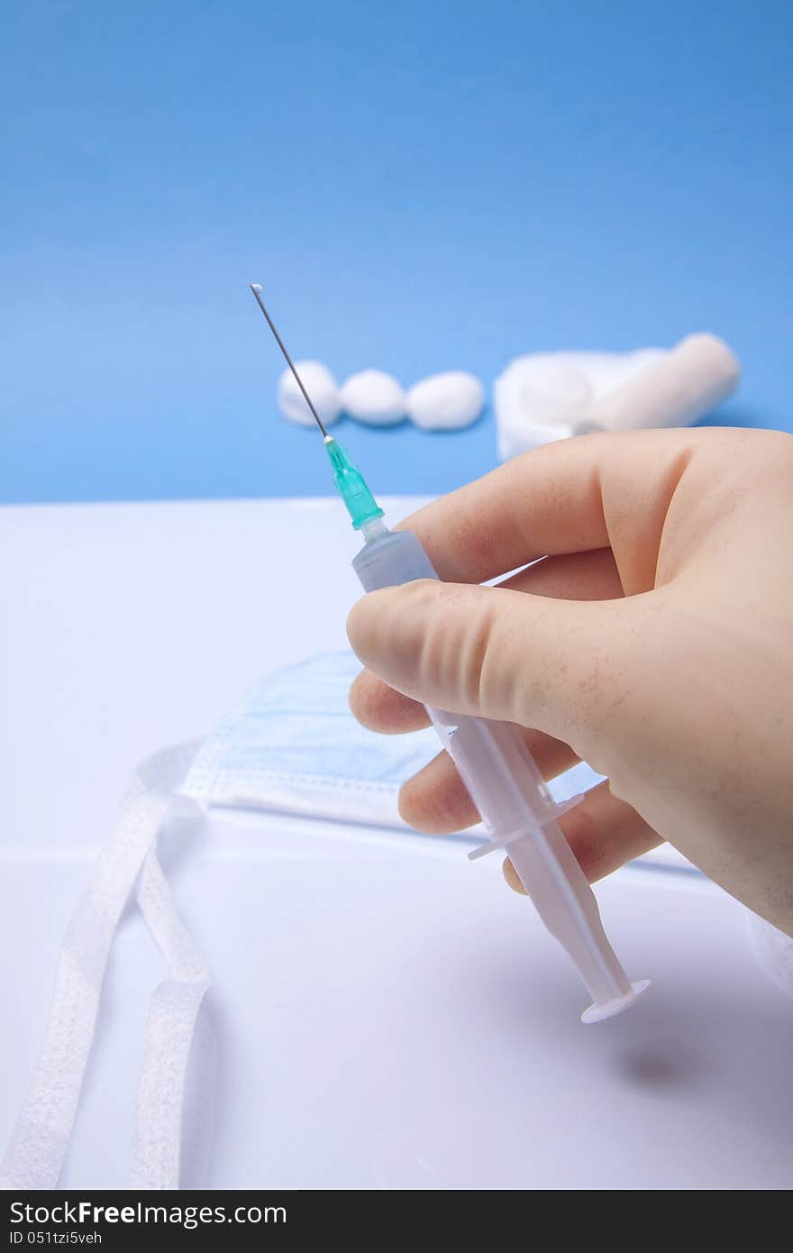 Doctor's Hand Holding Syringe On A Blue Background