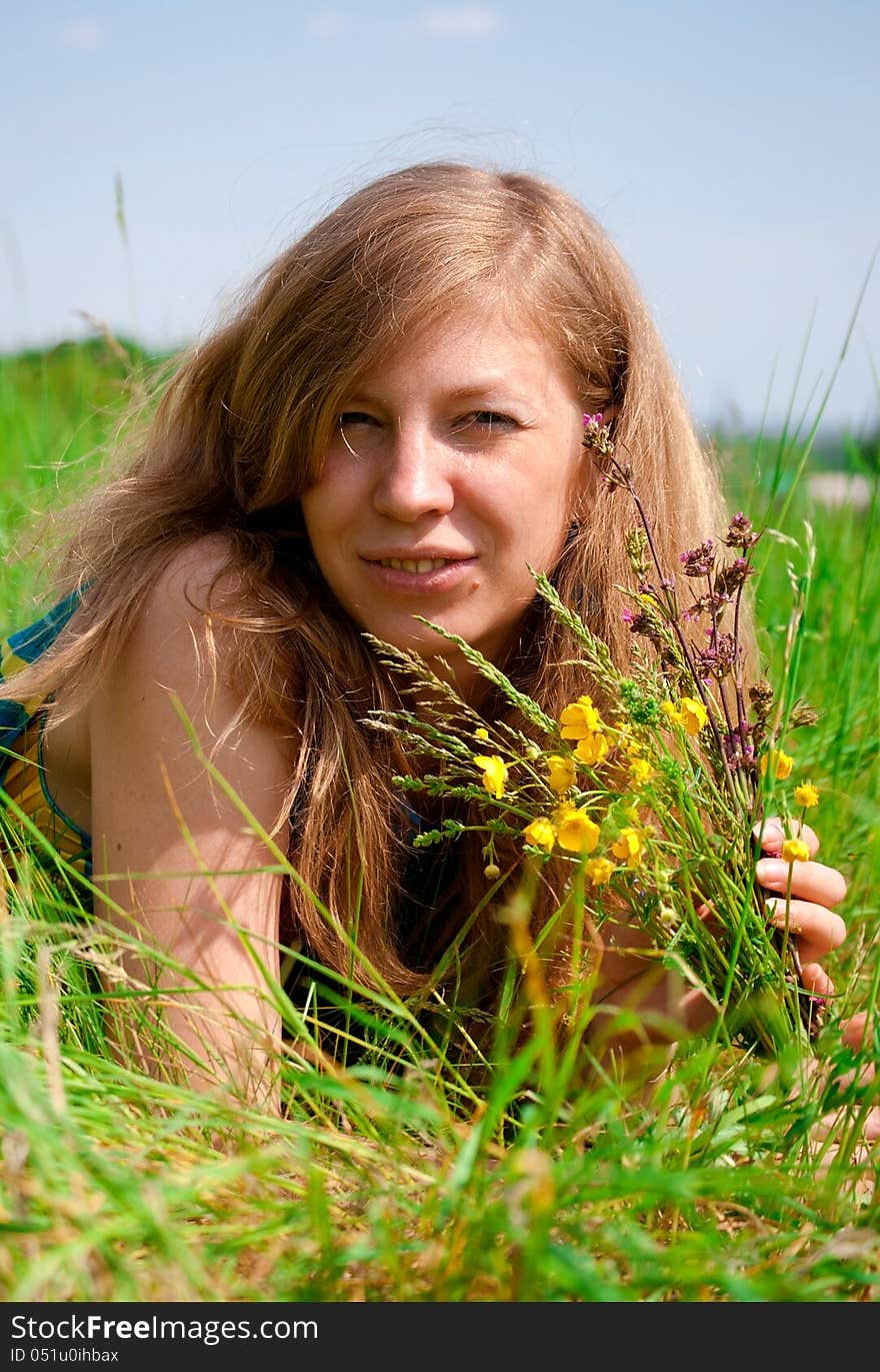 Young woman resting outdoors, holding flowers. Young woman resting outdoors, holding flowers