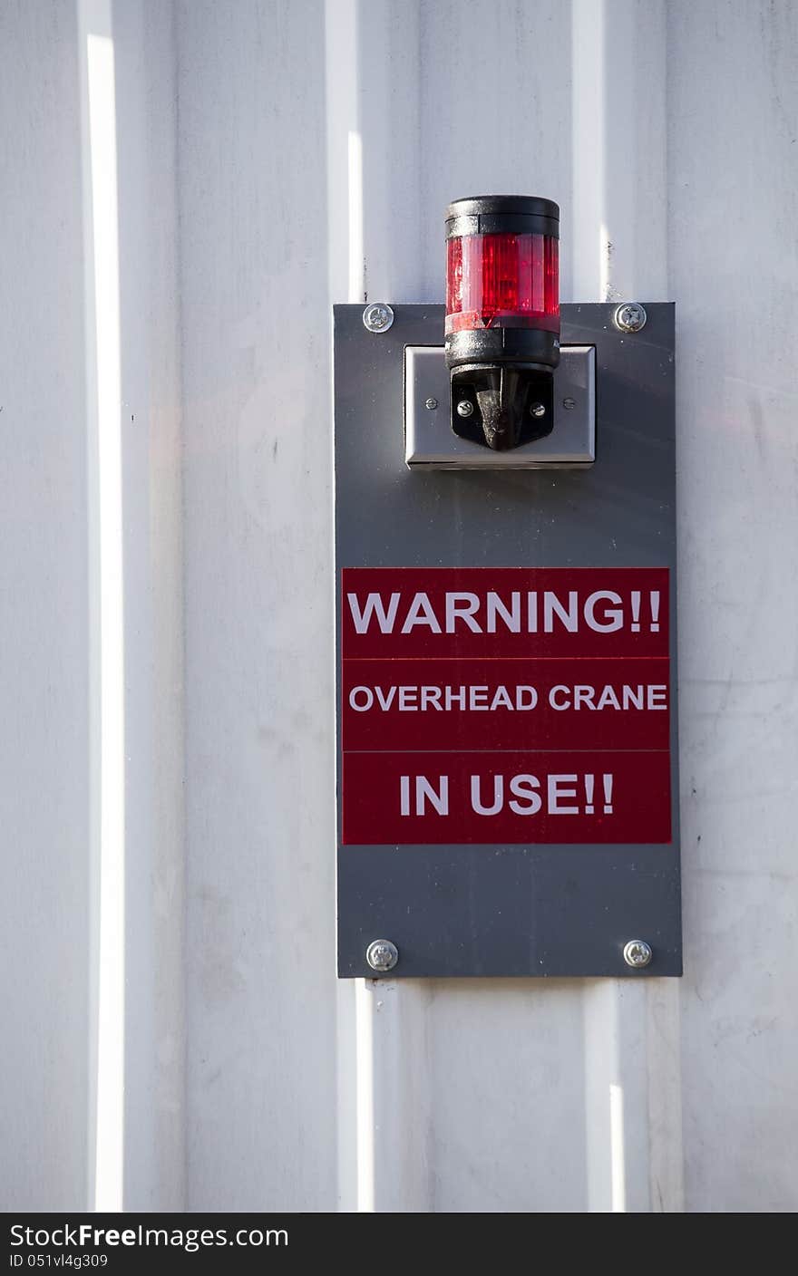 White sheet metal wall with mounted red safety light. White sheet metal wall with mounted red safety light.