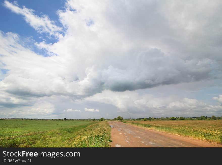 Cumulus Clouds Above The Road In The Steppe.