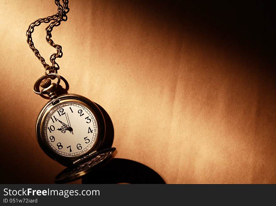 Vintage pocket watch with chain on old paper under beam of light. Vintage pocket watch with chain on old paper under beam of light