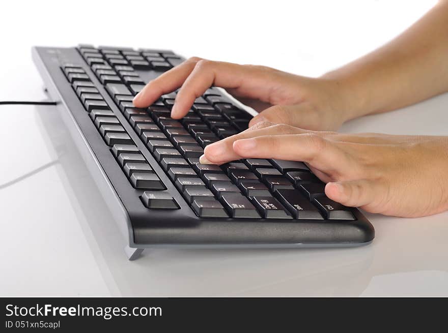 Woman hand typing on black computer keyboard over white background. Woman hand typing on black computer keyboard over white background