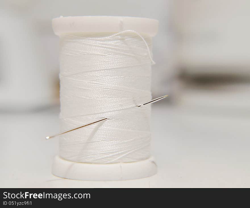 White thread on spool, standing position, with needle