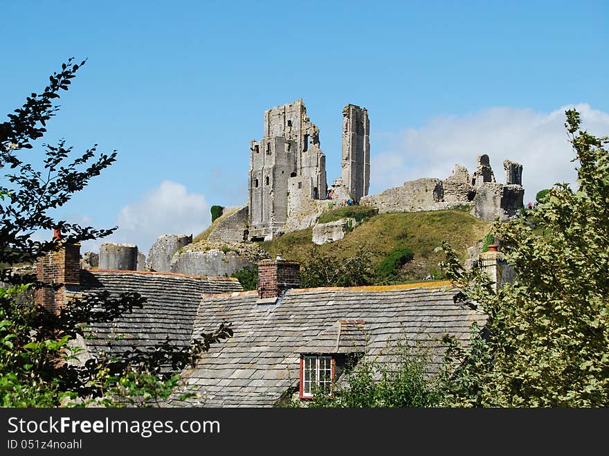 Ruined Corfe Castle, village roofs in foreground. Ruined Corfe Castle, village roofs in foreground