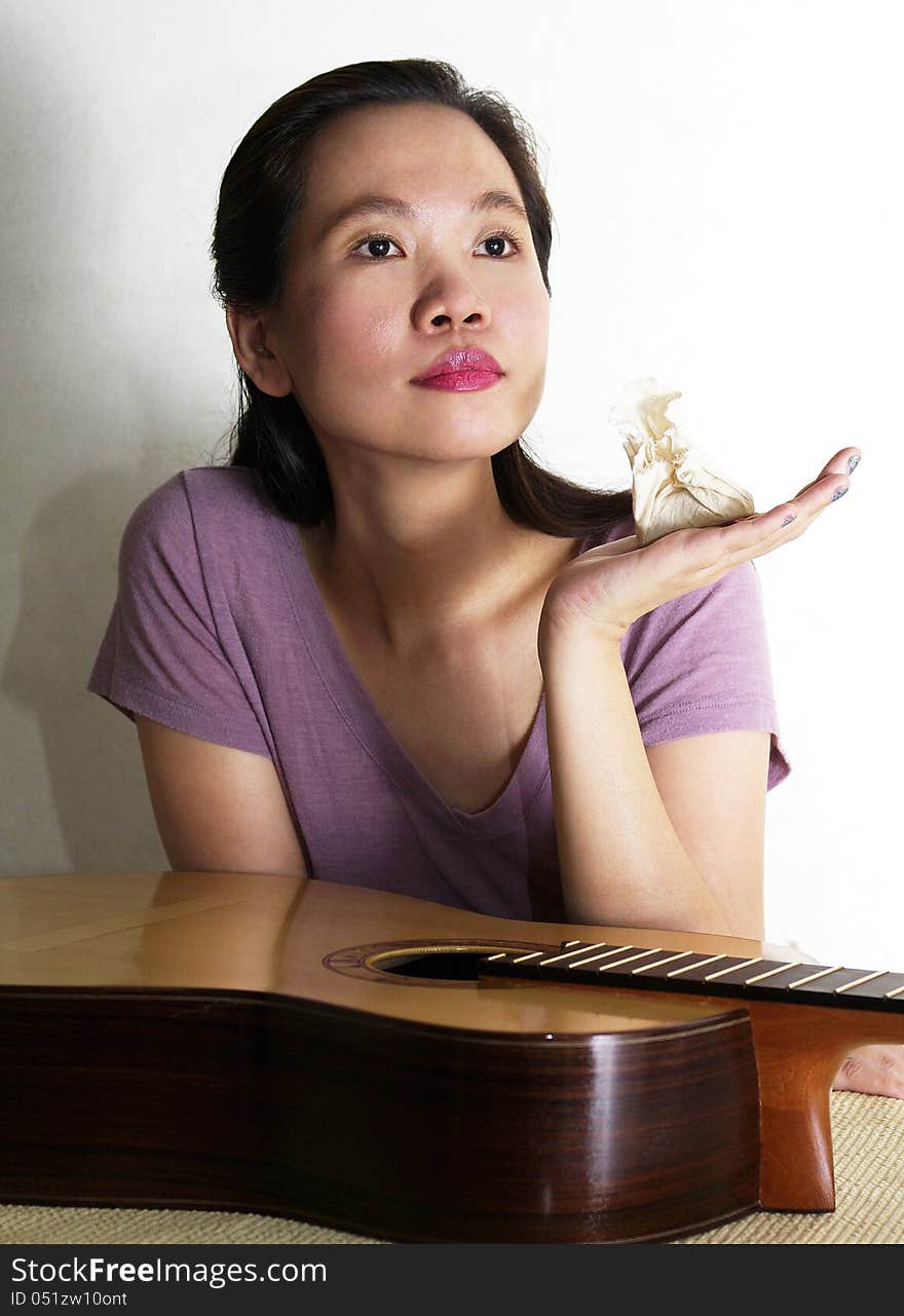 A portrait of attracttive asian woman varnishing guitar. A portrait of attracttive asian woman varnishing guitar