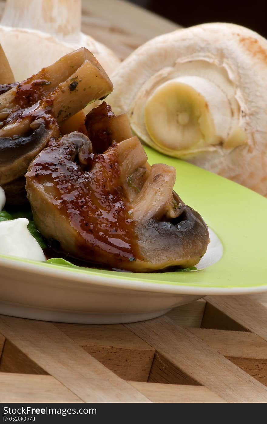 Cooked Grill Champignons with Sauce and Sour Cream Plate closeup on Wood Square background and Raw Mushrooms. Cooked Grill Champignons with Sauce and Sour Cream Plate closeup on Wood Square background and Raw Mushrooms