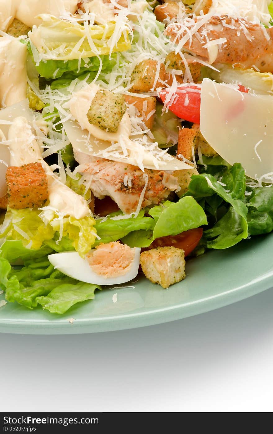 Caesar Salad with Grilled Chicken Breast, Garlic Crouton, Romaine Lettuce, Cherry Tomato, Eggs, Sauce and Grated Parmesan Cheese closeup on Green Plate