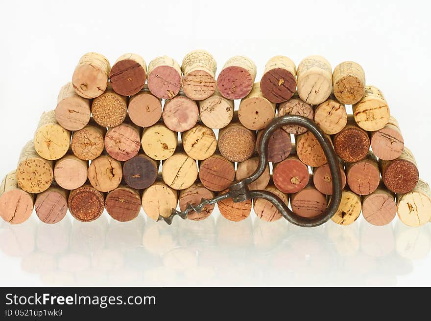 Vintage corkscrew against of the stack of wine corks with reflection on the glass table. Vintage corkscrew against of the stack of wine corks with reflection on the glass table