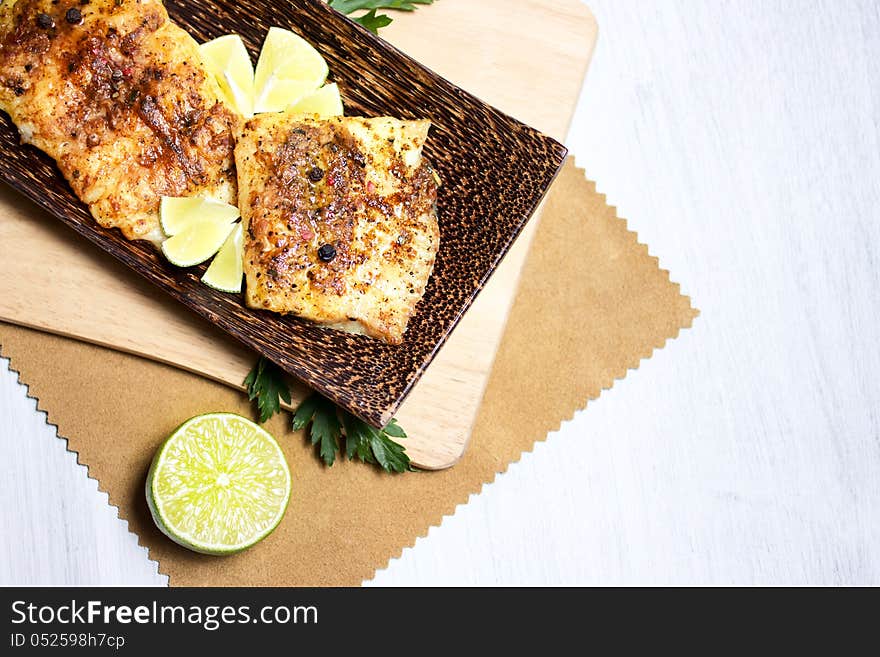 Fried white fish, served with lime, on wooden tableware. Fried white fish, served with lime, on wooden tableware