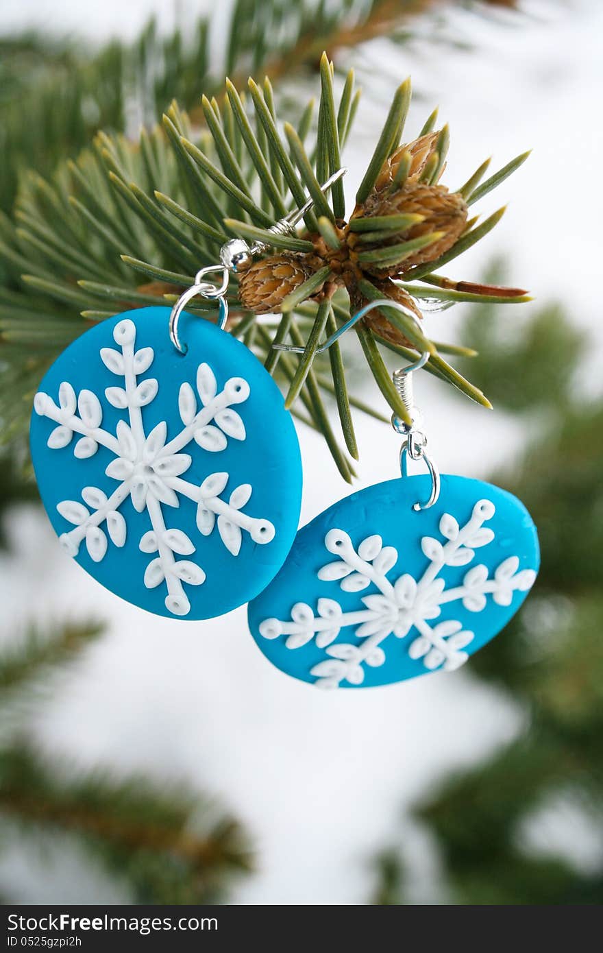 Two blue snowflake model earrings for present with a pin tree branch. Two blue snowflake model earrings for present with a pin tree branch