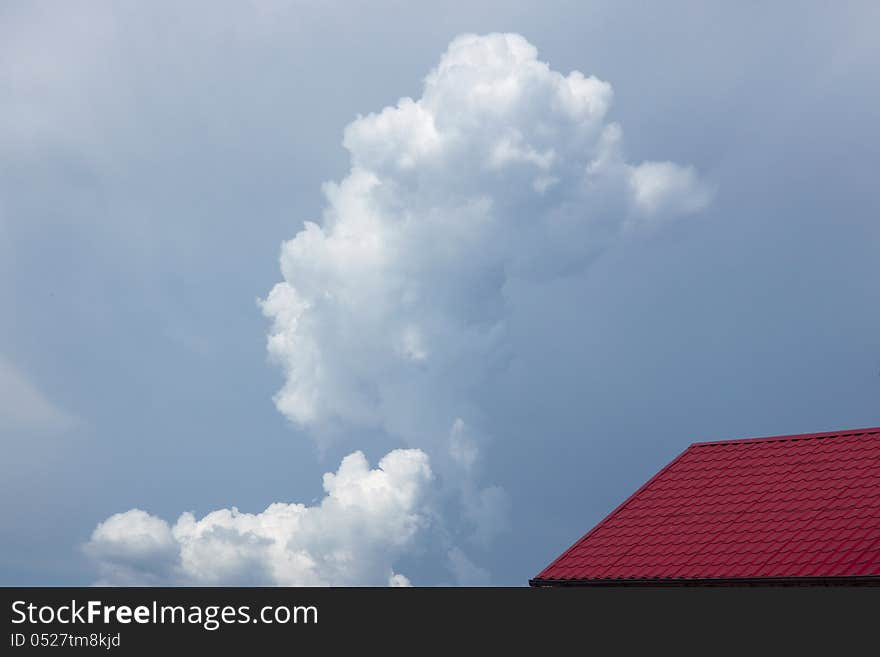 Red house roof  on  blue sky with clouds