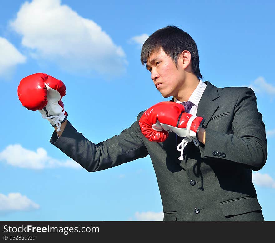 Businessman and hand boxing glove ready to fight over blue sky. Businessman and hand boxing glove ready to fight over blue sky