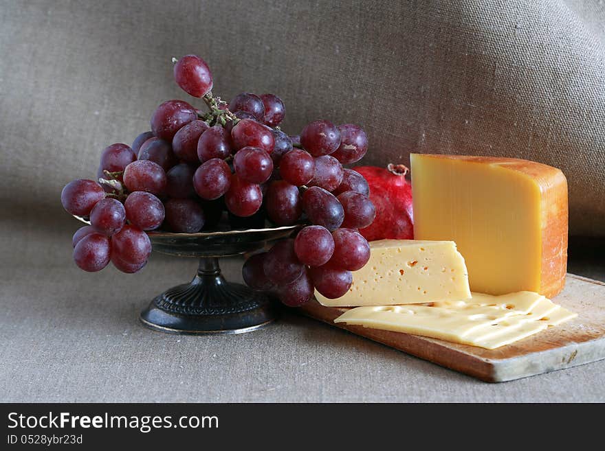 Still life with few sorts of cheese on wooden hardboard near fruits. Still life with few sorts of cheese on wooden hardboard near fruits