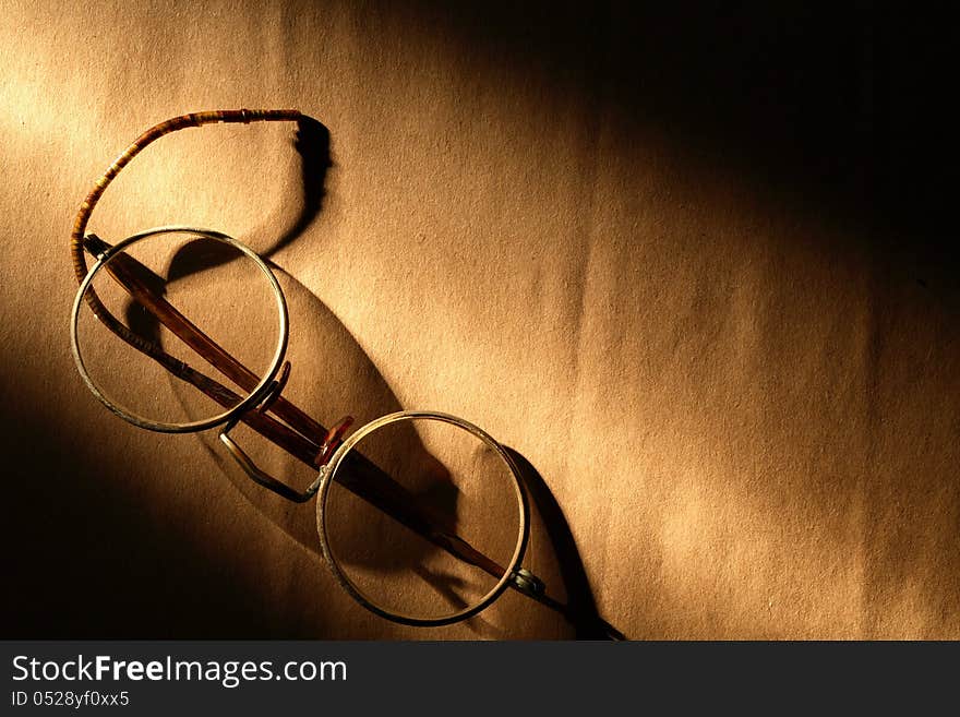 Old spectacles on paper surface under beam of light