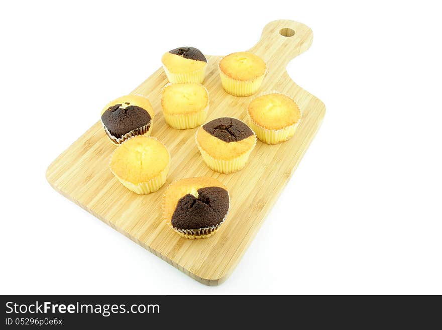 Plain and chocolate muffins on a wooden board. On a white background.