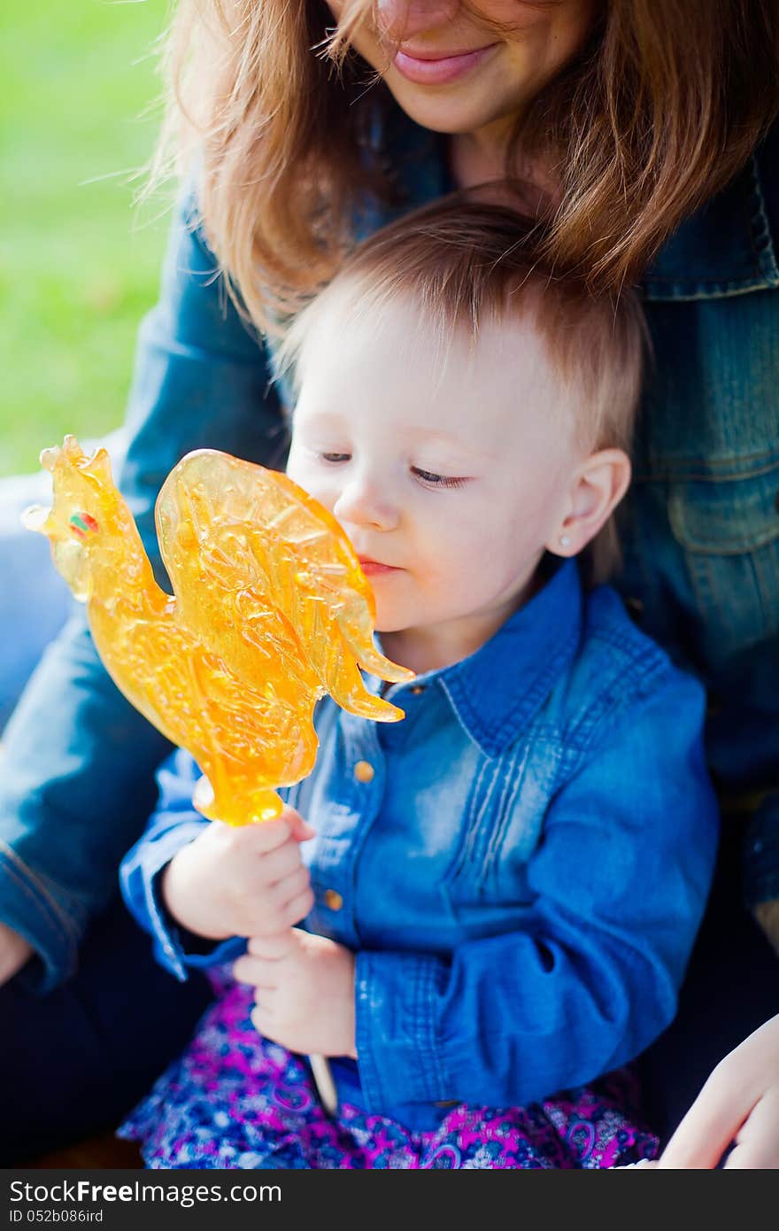 Little girl holding a cockerel-shaped lollipop. Little girl holding a cockerel-shaped lollipop