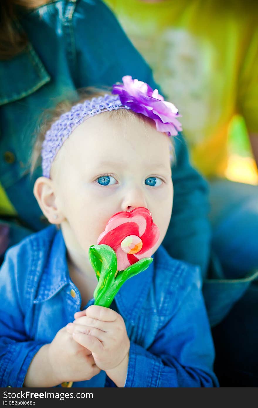 Little girl licking sweet flower-shaped lollipop. Little girl licking sweet flower-shaped lollipop