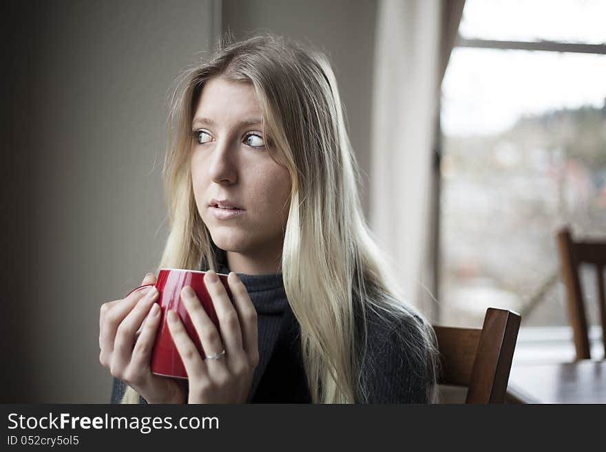 Pretty young blonde woman drinking her morning coffee. Pretty young blonde woman drinking her morning coffee.