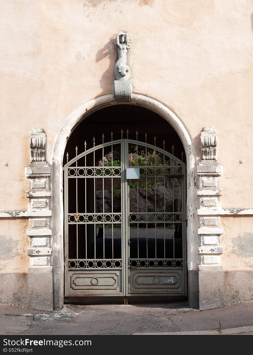 Old gate in the arch of the house with a bas-relief of the mermaids