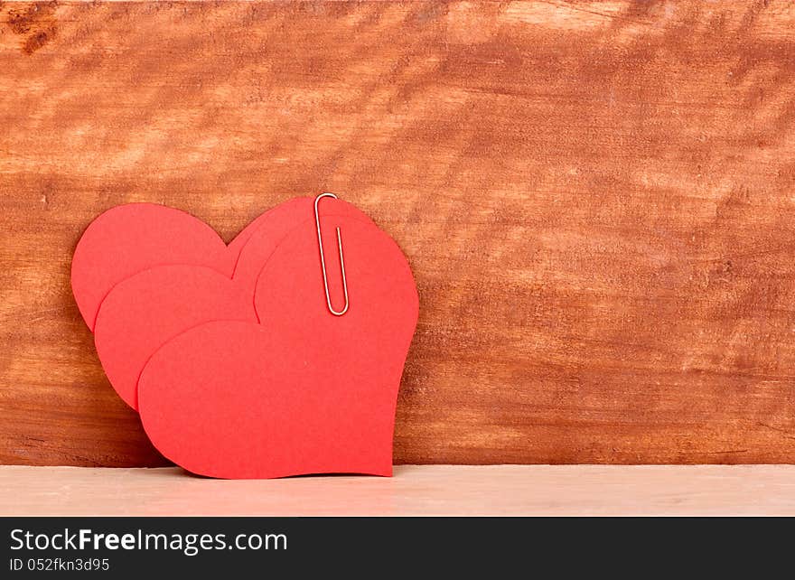 Heart and a clip on the wooden background