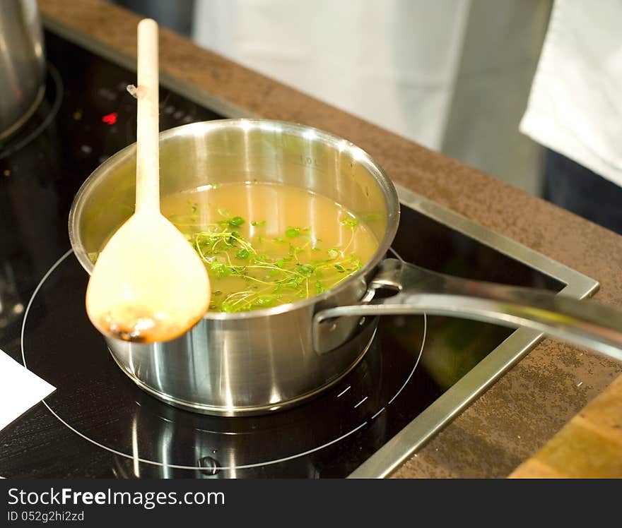 Fresh cooked vegetable soup on ceran oven. Image taken closeup with a wooden spoon on the steel pot.