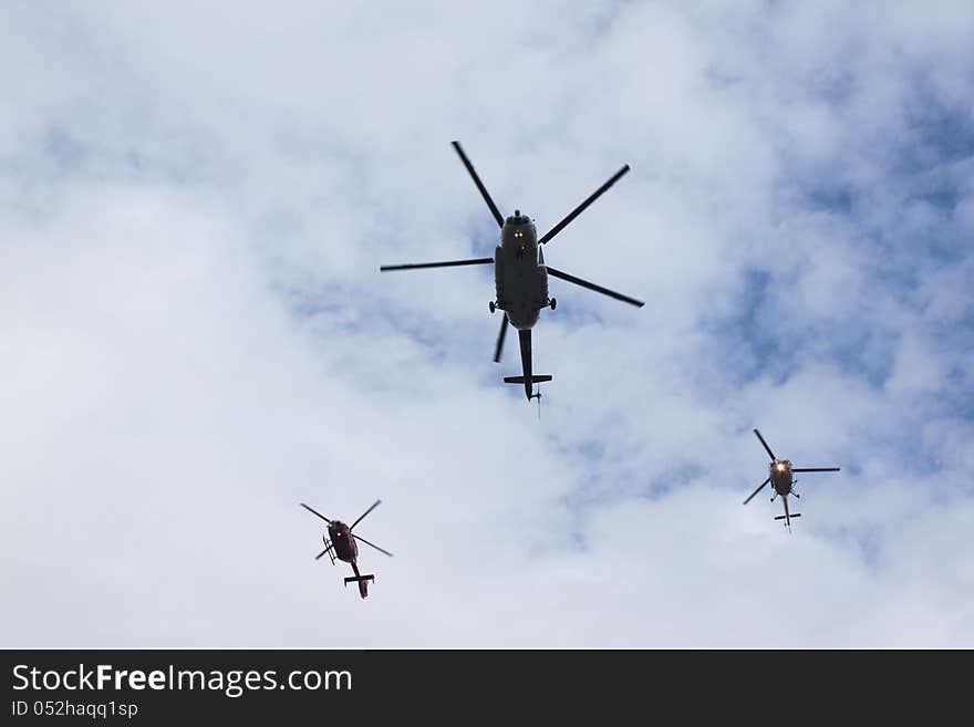 Helicopters flying in cloudy sky.