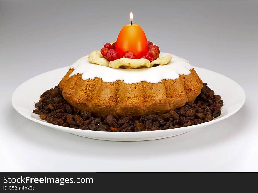 Simnel on white dish, dried fruit and a burning candle