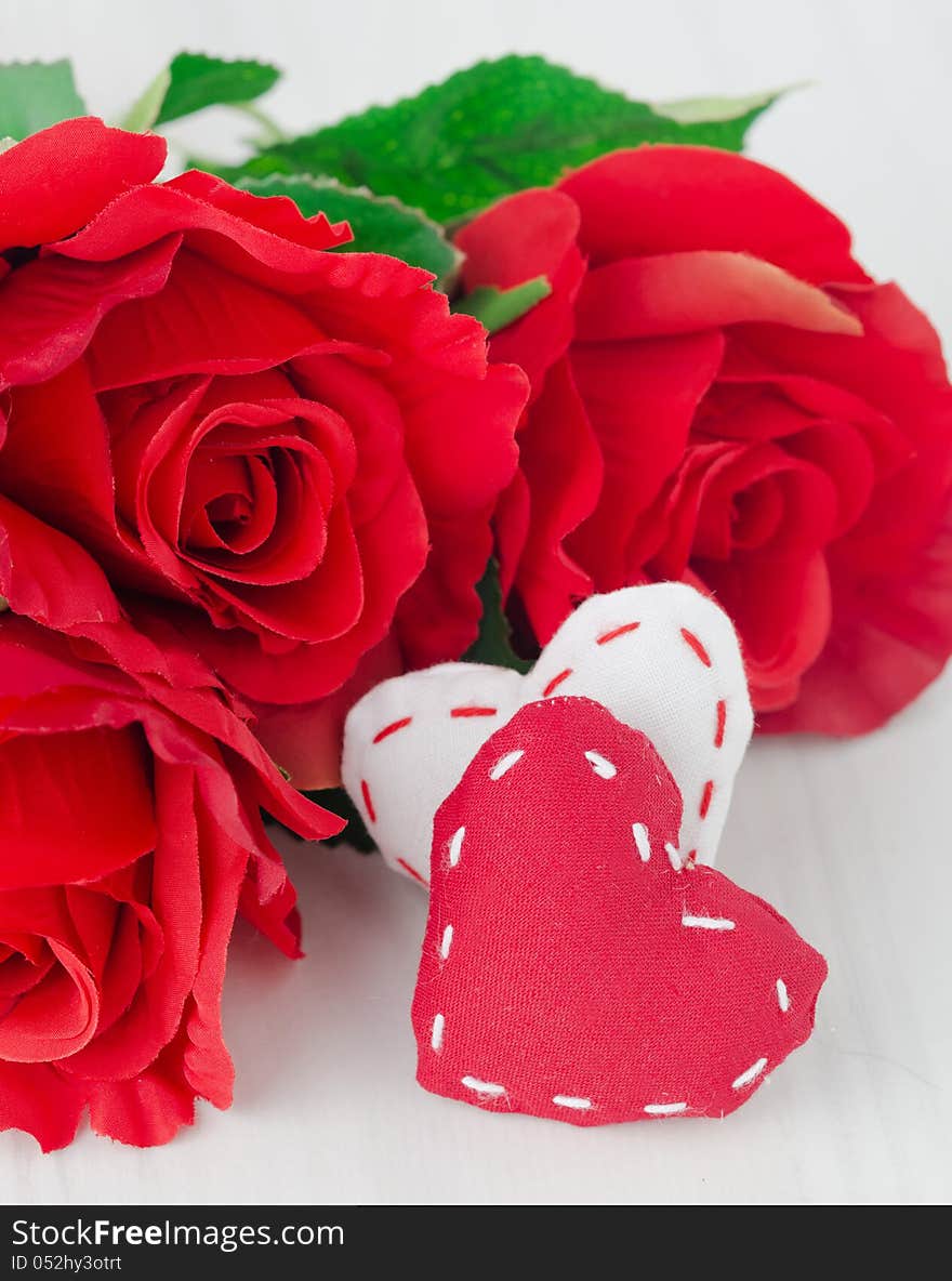 Canvas handmade hearts and red roses for Valentines day on a white table