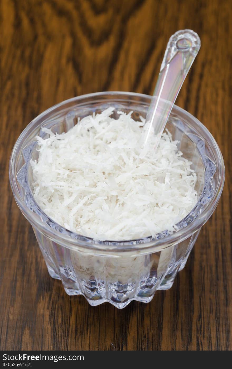 Unsweetened coconut flakes in a transparent jar on a wooden table