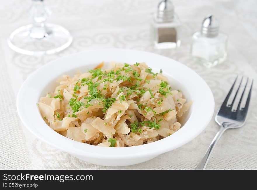 Fried Cabbage with greens and eggs in the white plate closeup