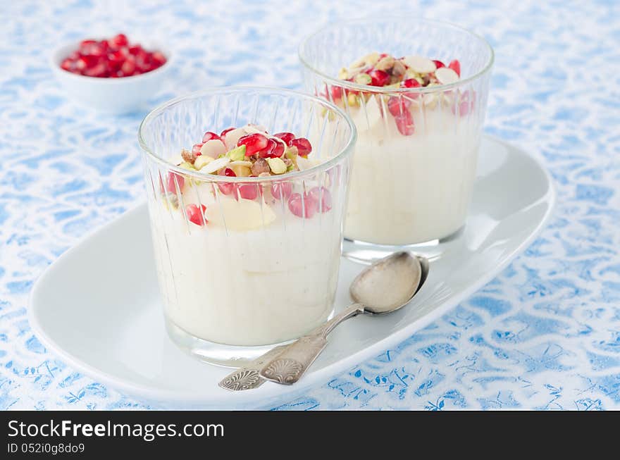 Semolina dessert with pomegranate seeds and pistachios in glass beakers on a plate horizontal. Semolina dessert with pomegranate seeds and pistachios in glass beakers on a plate horizontal