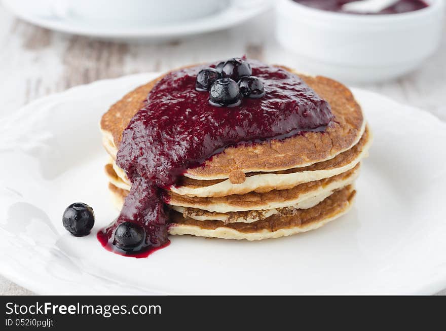 Stack of pancakes with black currant jam on the plate closeup, horizontal