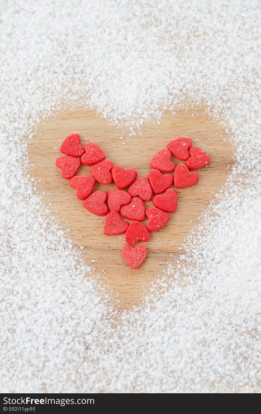 Sugar hearts in the form of heart on a board sprinkled with powdered sugar on a wooden board