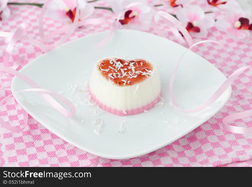 Two-layer cream dessert in the form of heart with coconut on a plate horizontal