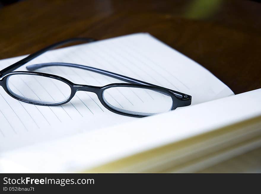 Close up eyeglasses put on open notebook